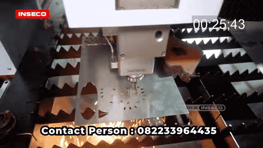 Close-up dari mesin CNC laser cutting yang sedang bekerja, memotong stainless steel dengan percikan api yang terlihat.