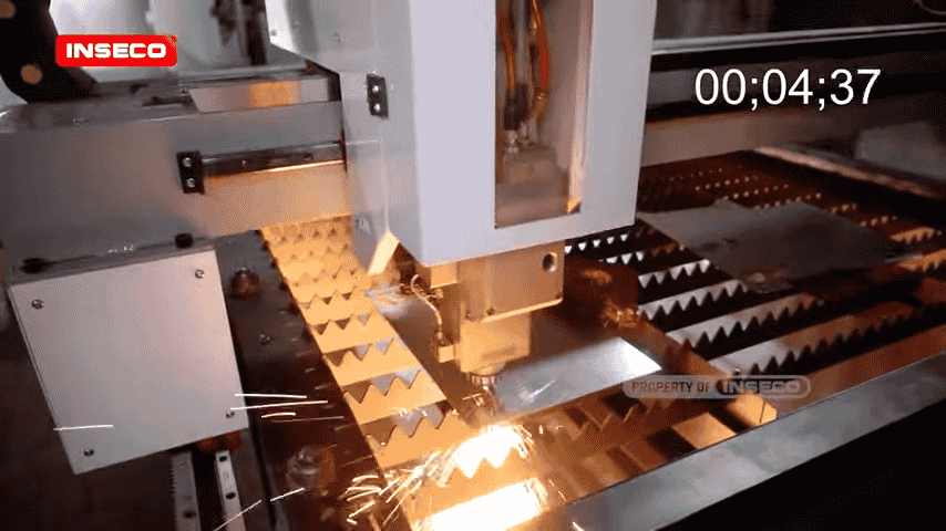 Gambar close-up lainnya dari proses pemotongan CNC laser, di mana laser fokus pada lembaran logam dengan percikan api yang terlihat.
