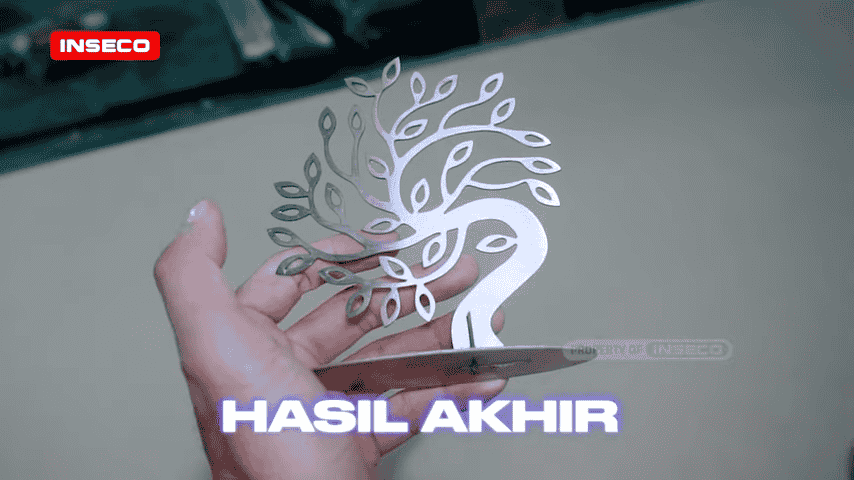 Produk akhir, desain pohon stainless steel yang dipotong dengan indah, dipegang dengan tangan, menunjukkan detail rumit yang dicapai melalui proses pemotongan CNC laser