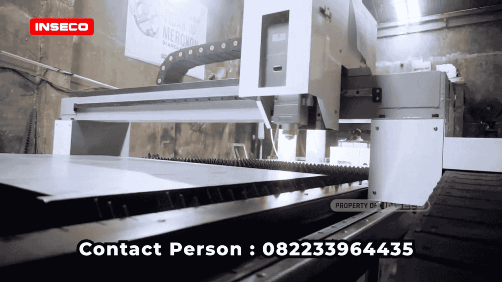 Close-up mesin pemotong laser Inseco, fokus pada area pemotongan, menunjukkan detail peralatan dan konveyor