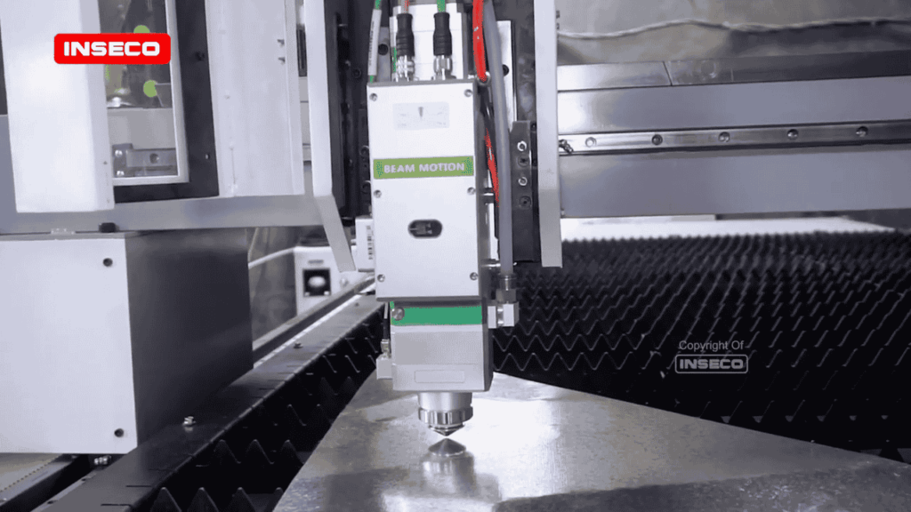 Pemandangan dekat laser head INSECO yang menghasilkan potongan presisi pada bahan logam