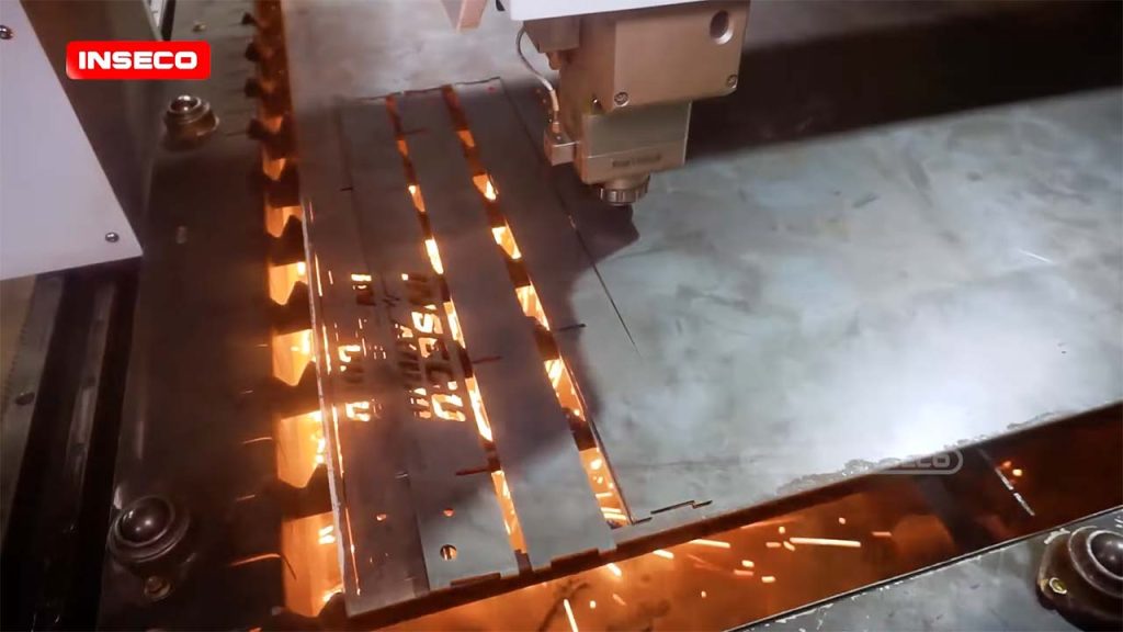 Proses kerja mesin cutting laser INSECO saat memotong plat besi dengan presisi tinggi menghasilkan percikan api